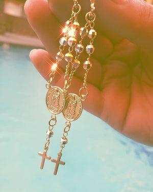 womens hand holding beautiful rosary virgen de guadalupe earrings
